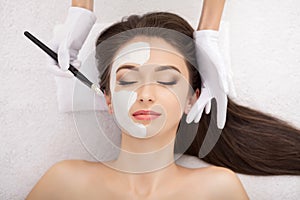 Spa therapy for young woman having facial mask at beauty salon -