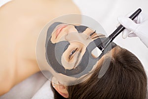 Spa therapy for young woman having facial mask at beauty salon -