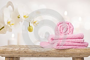 Spa towels on wooden table and orchid over abstract background