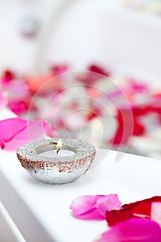 Spa treatment bathtub with petals and candles