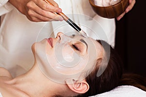 Spa treatment. Beautiful woman with facial mask at beauty salon.
