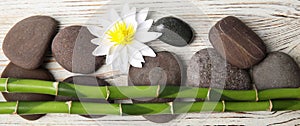 Spa treatment. Flat lay composition with stones, bamboo and lotus flower on white wooden table. Banner design