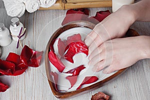 Spa treatment for skin with milk and rose petals, hands are placed in the bowl