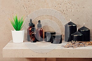 SPA treatments and scented candles standing on a shelf in dark brown flowers with a small potted plant. Aromatherapy body care