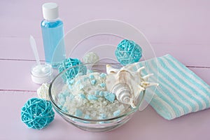 SPA treatments with sea salt and cleansers. Lotion, cream and blue bath towel on pink background. SPA concept, body and skin