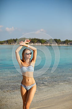 Spa wellness beach beauty woman in bikini swimwear relaxing and sun bathing near blue lagoon. Beautiful peaceful young