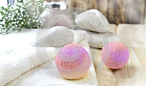 Spa or wellness bodycare setting. Still life image with bath bombs, stones, scrub, towel on wooden background.