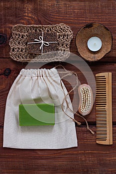 Spa wellness concept, natural coffee scrub, green conifer soap, eco bag, candle in coconut shell, peeling brush flat lay
