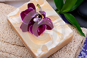 Spa Wellness Concept. Natural Loofah Sponge, Almond Goat`s milk Soap, White Towels, Basalt Stones, Bamboo and Orchid Flower