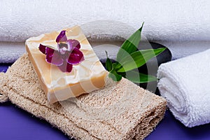 Spa Wellness Concept. Natural Loofah Sponge, Almond Goat`s milk Soap, White Towels, Basalt Stones, Bamboo and Orchid Flower