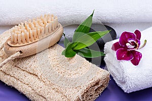 Spa Wellness Concept. Natural Loofah Sponge, Natural bristle Wooden Brush, White Towels, Basalt Stones, Bamboo and Orchid Flower