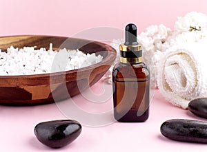 Spa and wellness with perfumed white lilac flowers water in wooden bowl and terry towel and bottle aromatherapy and black stones,