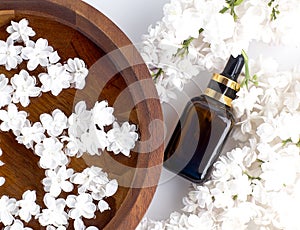 Spa and wellness with perfumed white lilac flowers water in wooden bowl and terry towel and bottle aromatherapy, top view, flat