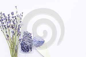 Spa and wellness setting with lavender flowers, sea salt, oil in a bottle, aroma candle on wooden white background