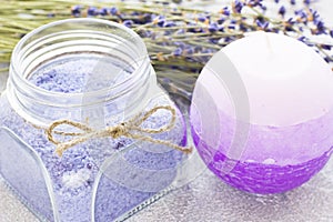 Spa and wellness setting with lavender flowers, sea salt, oil in a bottle, aroma candle on wooden white background