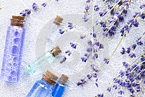 Spa and wellness setting with lavender flowers, sea salt, oil in a bottle, aroma candle on wooden white background