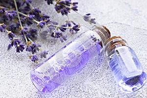 Spa and wellness setting with lavender flowers, sea salt, oil in a bottle, aroma candle on wooden white background