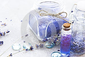 Spa and wellness setting with lavender flowers, sea salt, oil in a bottle, aroma candle on wooden white background