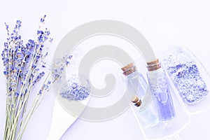 Spa and wellness setting with lavender flowers, sea salt, oil in a bottle, aroma candle on wooden white background