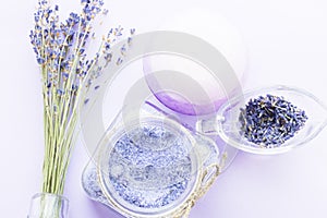 Spa and wellness setting with lavender flowers, sea salt, oil in a bottle, aroma candle on wooden white background