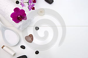 Spa setting with pink orchids, black stones and bath salts on wood background.