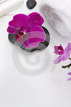 Spa or wellness setting with pink orchids ,towel and black stones.