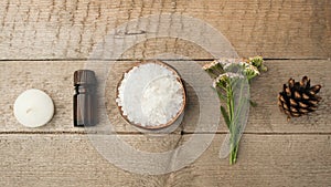 Spa and wellness setting with sea salt, oil essence, cones and candle on wooden background. Fall autumn wellness concept, Relax