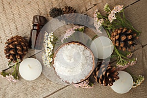 Spa and wellness setting with sea salt, oil essence, cones and candle on wooden background. Fall autumn wellness concept, Relax an