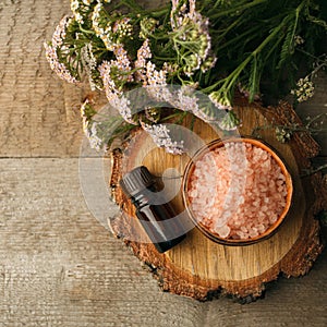 Spa and wellness setting with sea salt, oil essence, cones and candle on wooden background. Fall autumn wellness concept, Relax