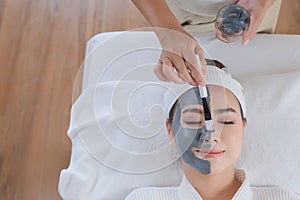 Spa woman applying facial clay mask.