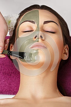 Spa Woman applying Facial clay Mask. Beauty Treatments. Close-up portrait of beautiful girl applying facial mask.Cosmetology. Body