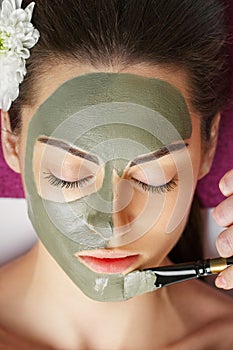 Spa Woman applying Facial clay Mask. Beauty Treatments. Close-up portrait of beautiful girl applying facial mask.Cosmetology. Body