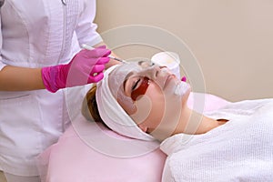 Spa Woman applying Facial cleansing Mask.