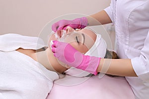 Spa Woman applying Facial cleansing Mask.