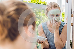 Spa Woman applying Facial green clay Mask. Beauty Treatments. Close-up portrait of beautiful girl applying facial mask