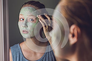 Spa Woman applying Facial green clay Mask. Beauty Treatments. Close-up portrait of beautiful girl applying facial mask