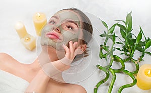 Spa Woman applying Facial green clay Mask. Beauty Treatments. Close-up portrait of beautiful girl in spa salon. Dayspa photo