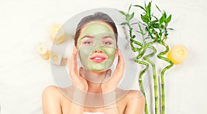 Spa Woman applying Facial green clay Mask. Beauty Treatments. Close-up portrait of beautiful girl in spa salon photo