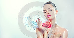 Spa woman. Beauty smiling girl with splashes of water and rose in her hands