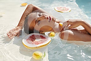 SPA Woman In Pool With Citrus. Beautiful Girl With Fresh Tropical Fruit Relaxing At Resort.