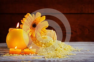 Spa yellow products setting. Sea salt ,towel and candles on dark wooden background