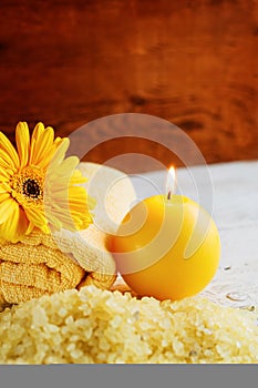 Spa yellow products setting. Sea salt ,towel and candles on dark wooden background