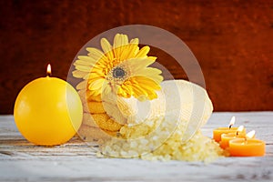 Spa yellow products setting. Sea salt ,towel and candles on dark wooden background