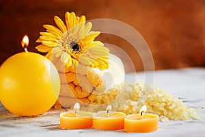 Spa yellow products setting. Sea salt ,towel and candles on dark wooden background