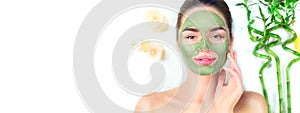 Spa. Young woman applying facial green clay mask in spa salon. Beauty treatments. Skincare