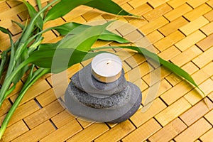 Spa, zen, massage concept. Bamboo leaves, black stones, lighting candle on wood background
