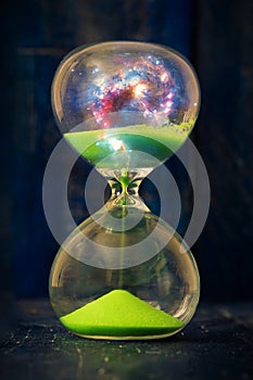 Space and galaxy in hourglass. Life time passing concept. Sand running through the bulbs of hourglass measuring passing