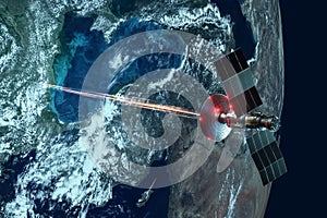 Space military satellite, a weapon in space shoots a laser against the background of the earth. Attack, technology, space war.