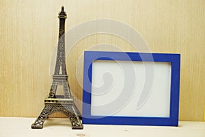 Space photo frame mock up with Eiffel tower souvenir on wooden background