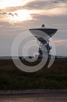 Space radar antenna. Satellite dish at sunset with cloudy sky